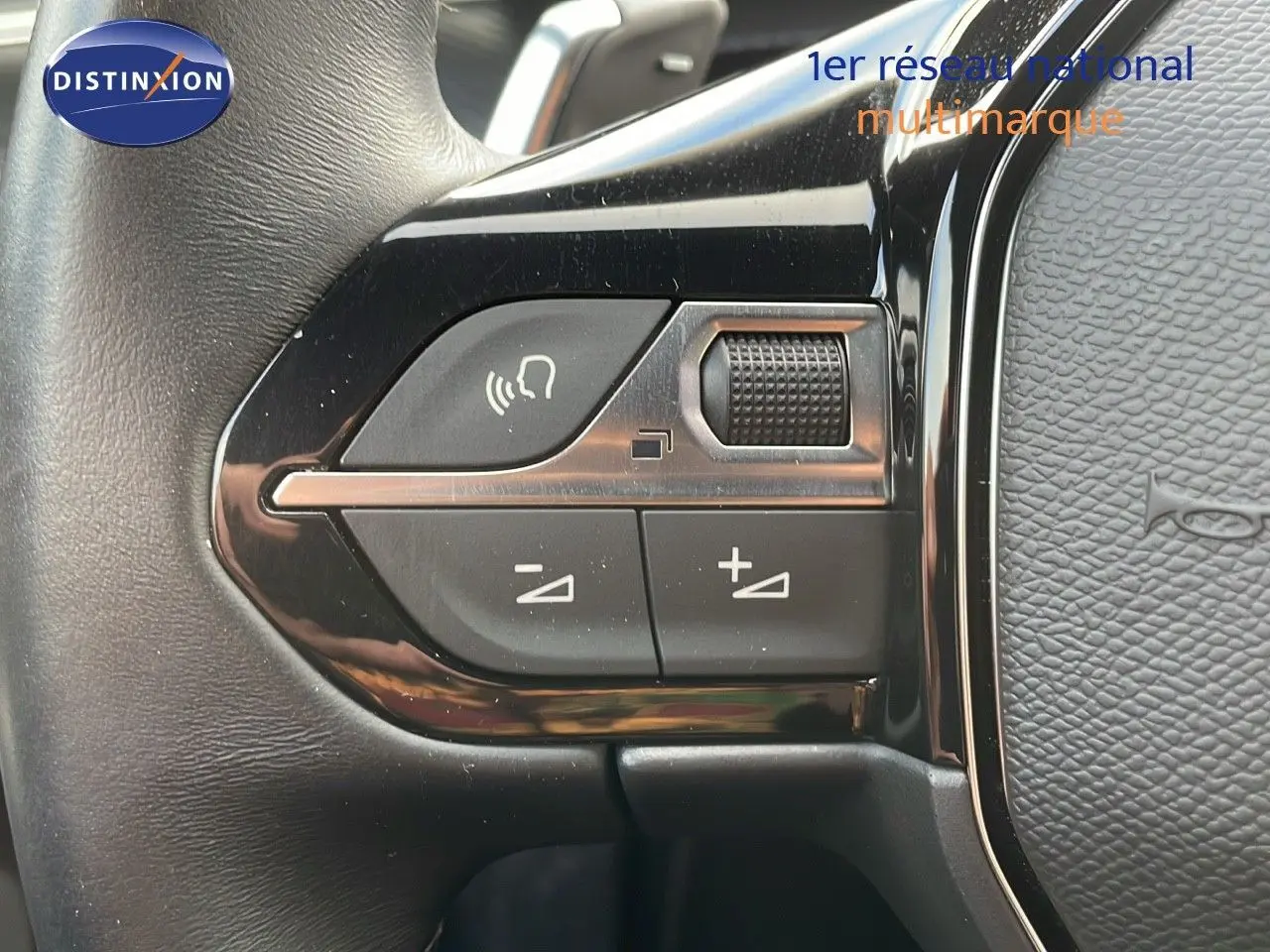 Gros plan sur les commandes de volume et de voix au volant cuir noir de la Peugeot 508 Gris Platinium 2023.