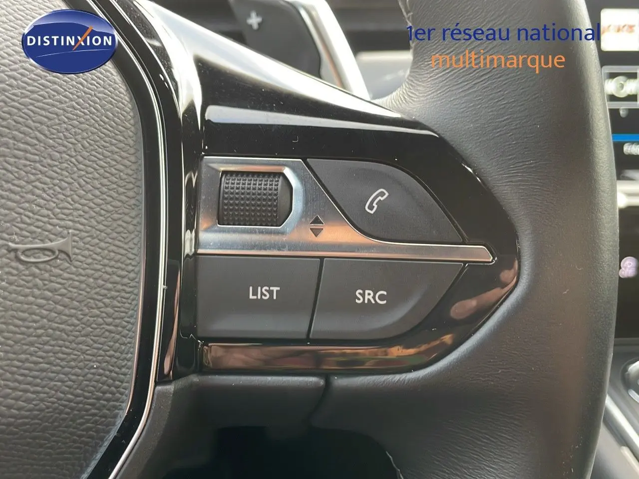 Gros plan sur les commandes gauche du volant en cuir noir du Peugeot 508 gris platinium, avec boutons LIST et SRC visibles.