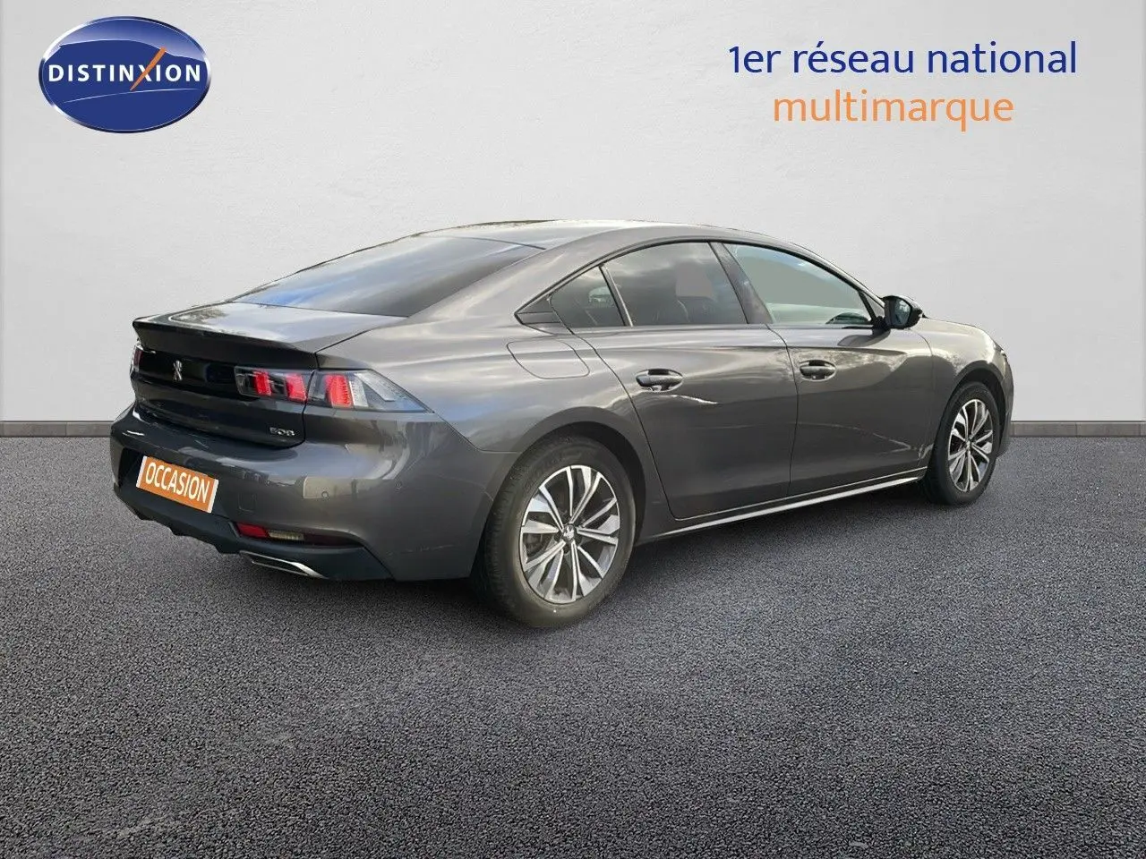 Peugeot 508 gris platinium métal vue 3/4 arrière côté droit sur sol gris avec logo Distinxion en arrière-plan.