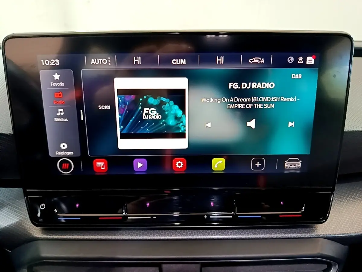 Écran tactile central allumé du tableau de bord du SEAT Leon gris clair, affichant la radio FG DJ Radio.
