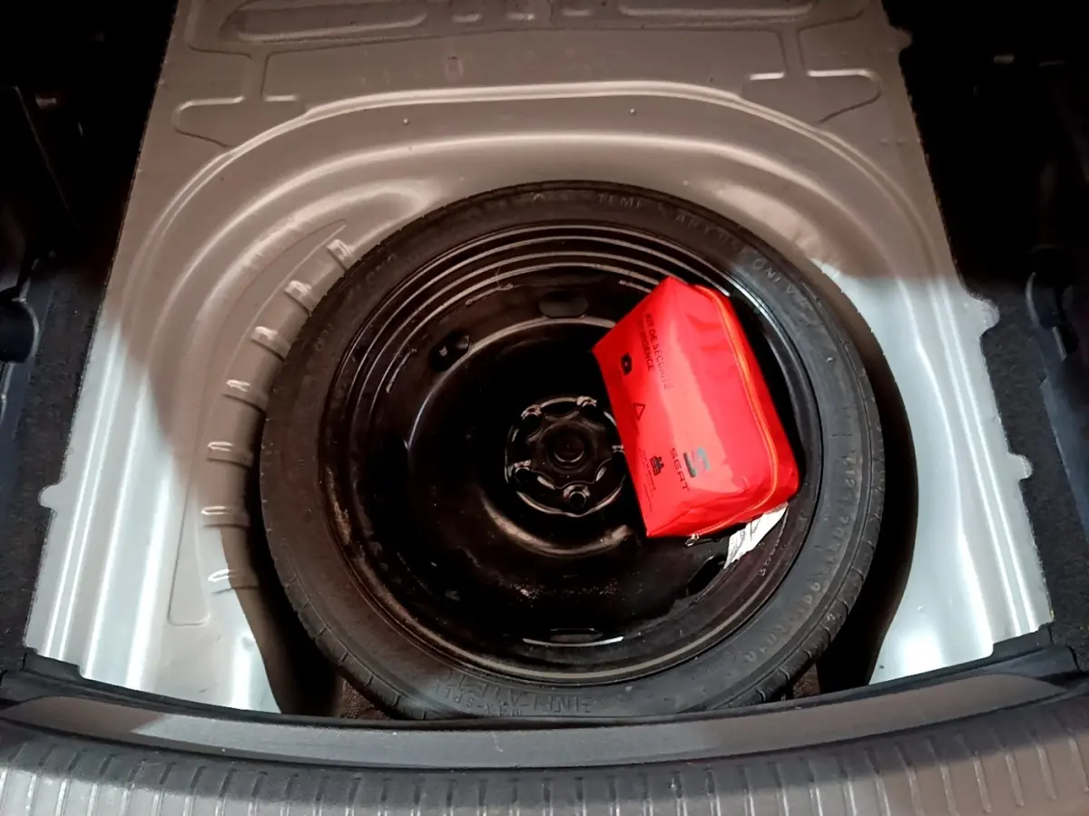 Roue de secours galette noire avec trousse de sécurité rouge dans le coffre d'une SEAT LEON gris clair 2022.