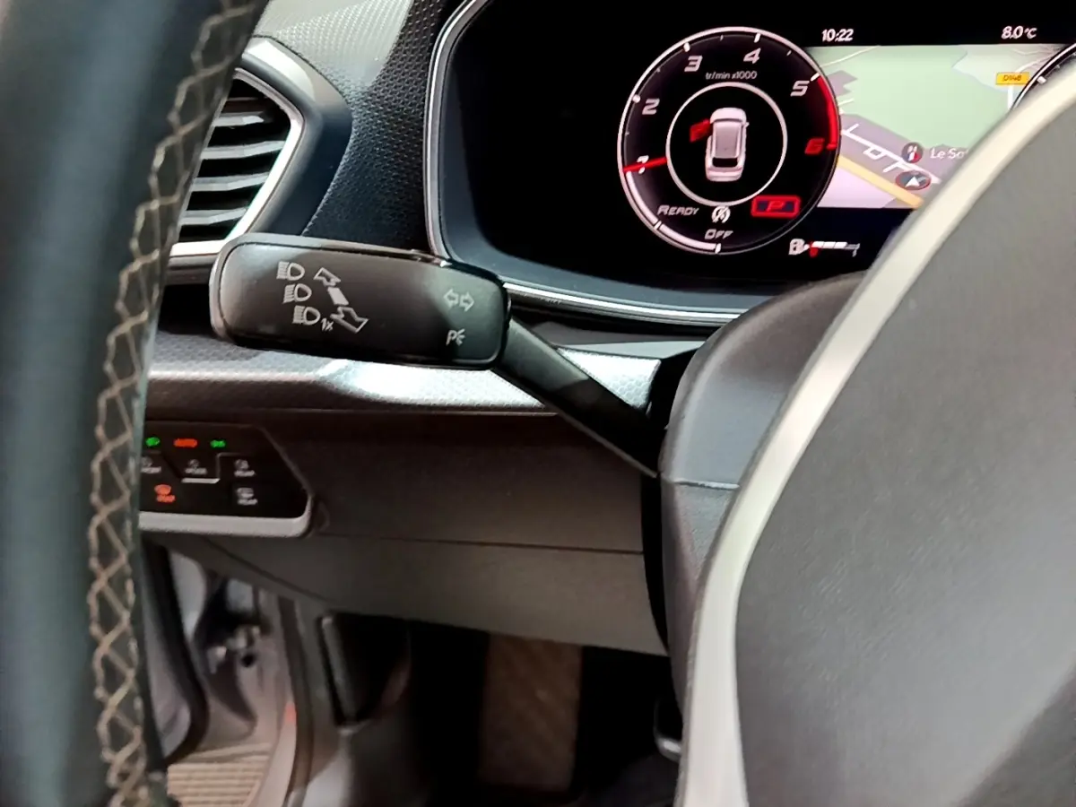 Vue rapprochée du commodo gauche et du tableau de bord numérique du SEAT Leon gris clair 2022, affichage 10,2 pouces.