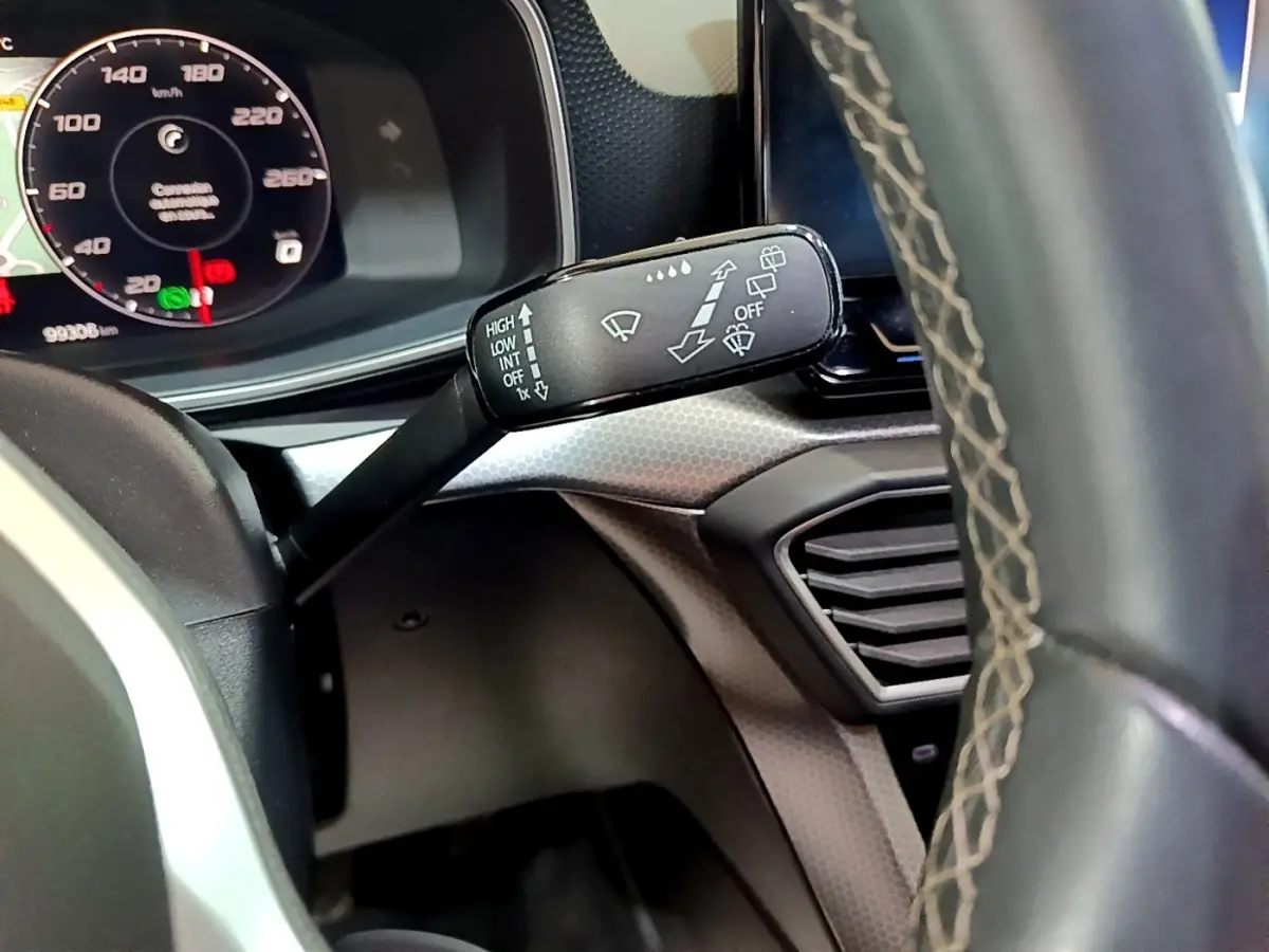 Gros plan sur la manette d'essuie-glace à gauche du volant cuir du tableau de bord d'une SEAT Leon gris clair 2022.