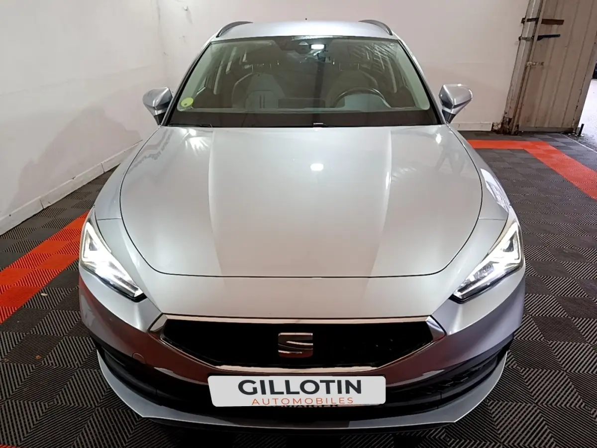 Vue frontale d'une SEAT LEON gris clair 2022 avec phares LED allumés dans un garage fermé.