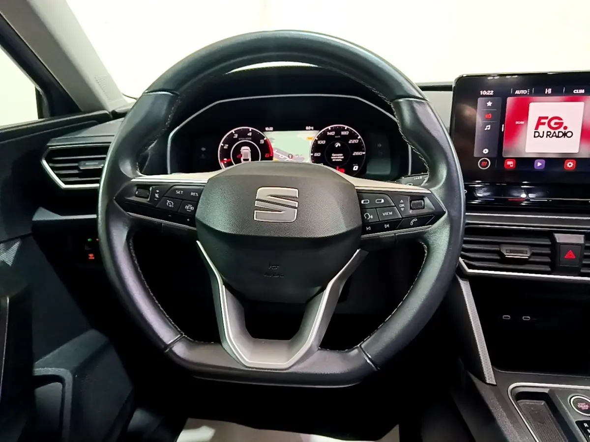 Vue frontale du volant en cuir noir du SEAT LEON 2022 avec tableau de bord numérique et écran tactile multimédia.