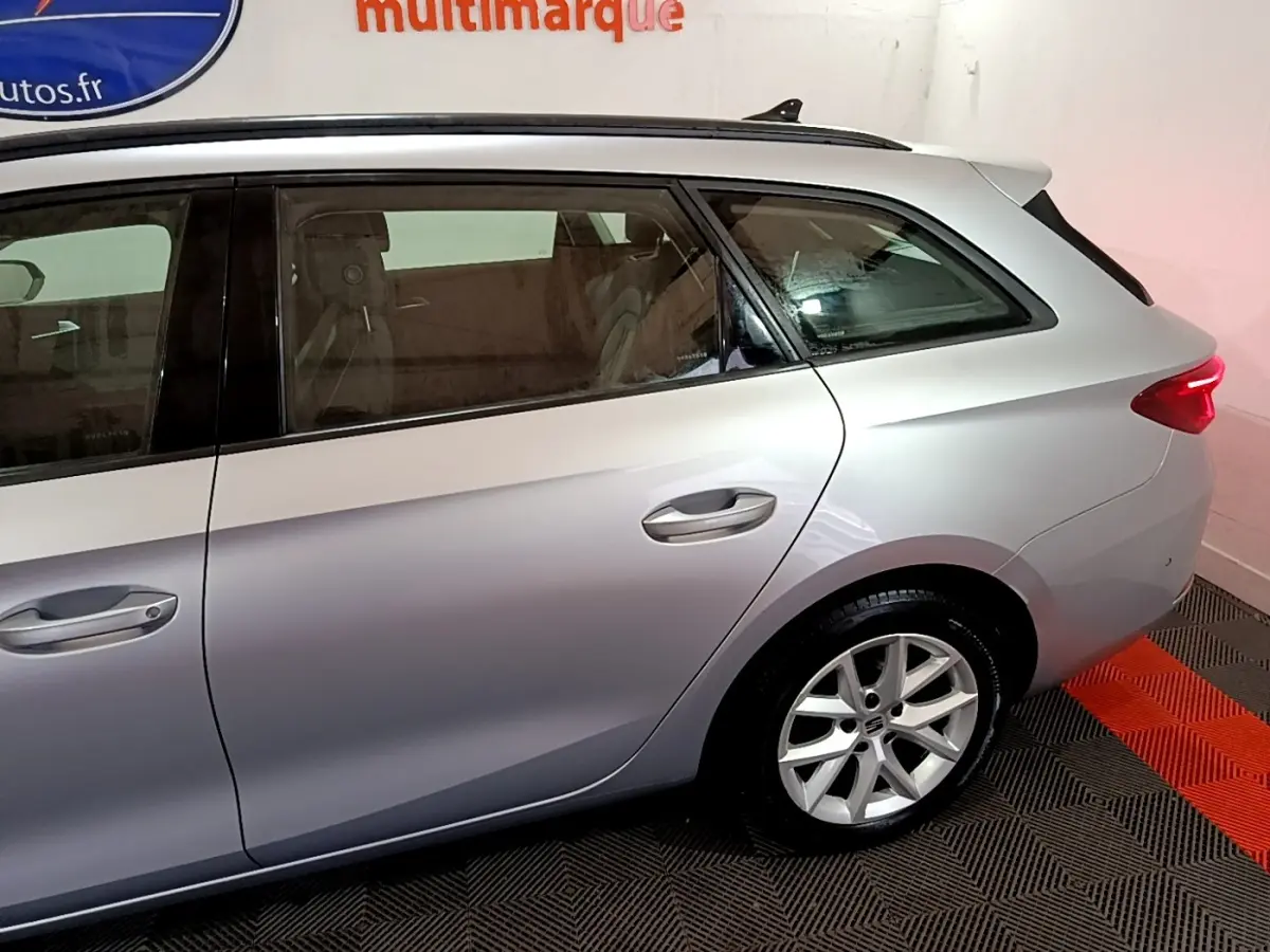 Vue latérale droite arrière d'une SEAT LEON gris clair avec jante alliage et feux arrière LED allumés.