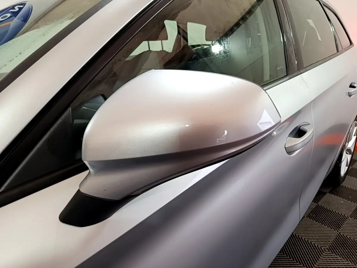 Gros plan sur le rétroviseur côté gauche gris clair du SEAT LEON 2022, avec partie de la porte visible.