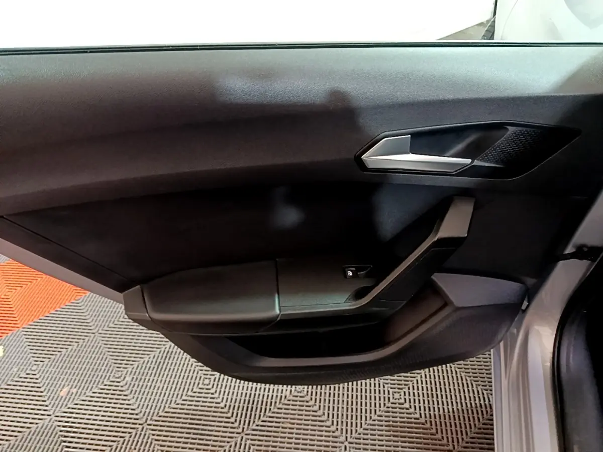 Détail de la porte côté conducteur noire du SEAT LEON gris clair 2022 avec poignée argentée et commande de vitre.