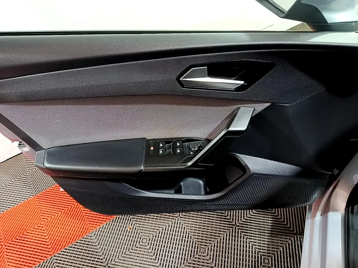 Gros plan sur la porte côté gauche d'une SEAT LEON gris clair, avec commandes électriques et poignée noire.