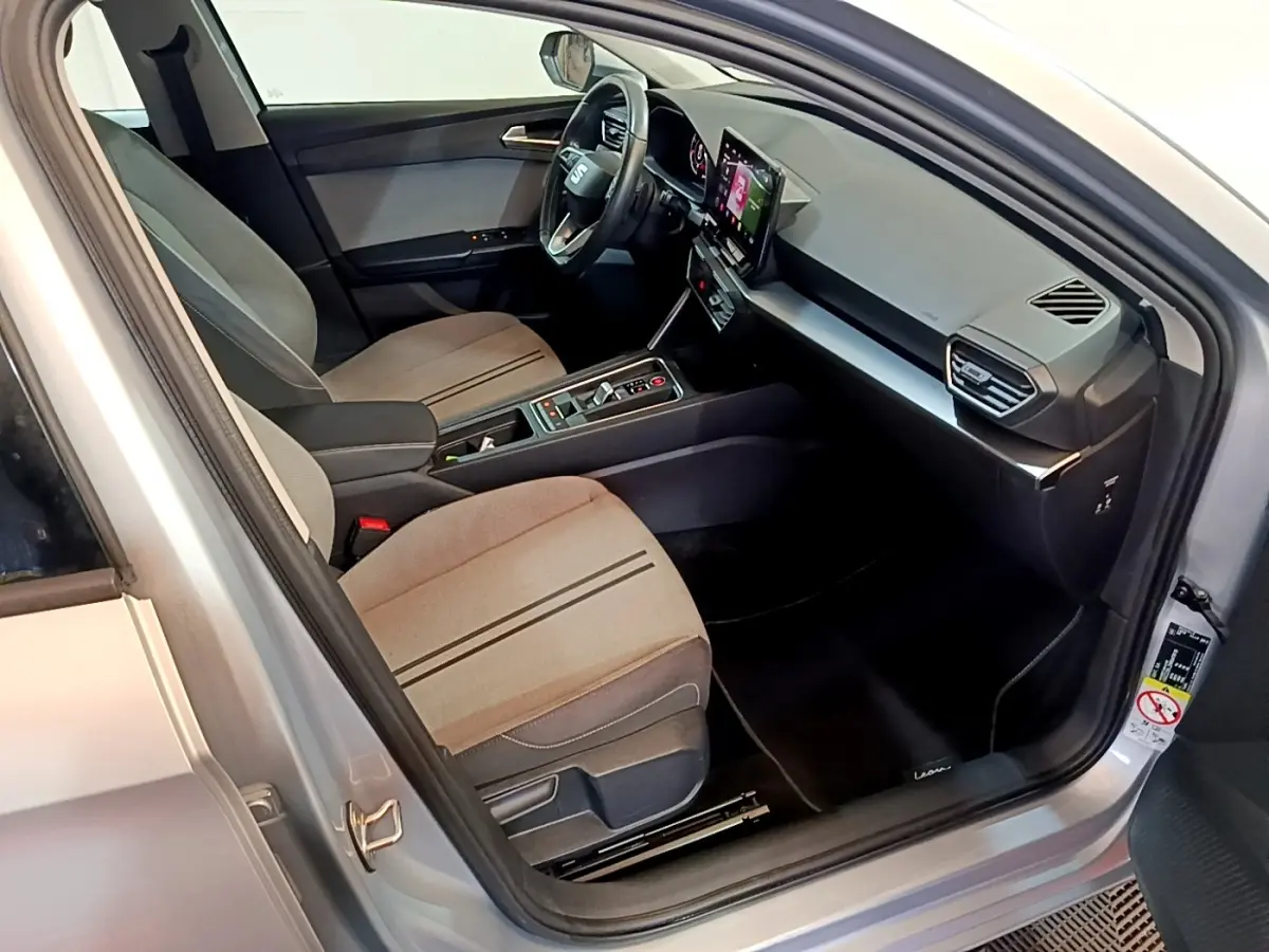 Intérieur côté conducteur du SEAT Leon gris clair 2022, avec tableau de bord moderne et écran tactile central visible.