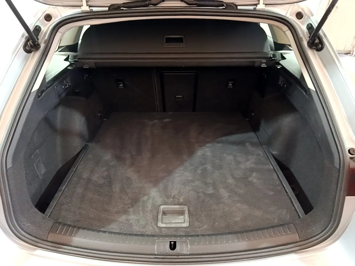 Coffre ouvert vu de l'arrière d'une SEAT LEON gris clair, espace de chargement spacieux et tapis noir.