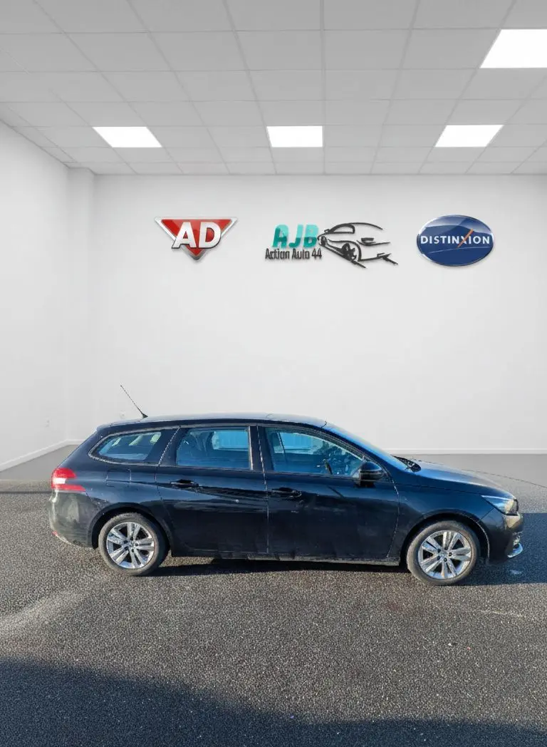 Peugeot 308 SW noire vue de profil côté gauche, avec jantes alliage et vitres arrière surteintées.