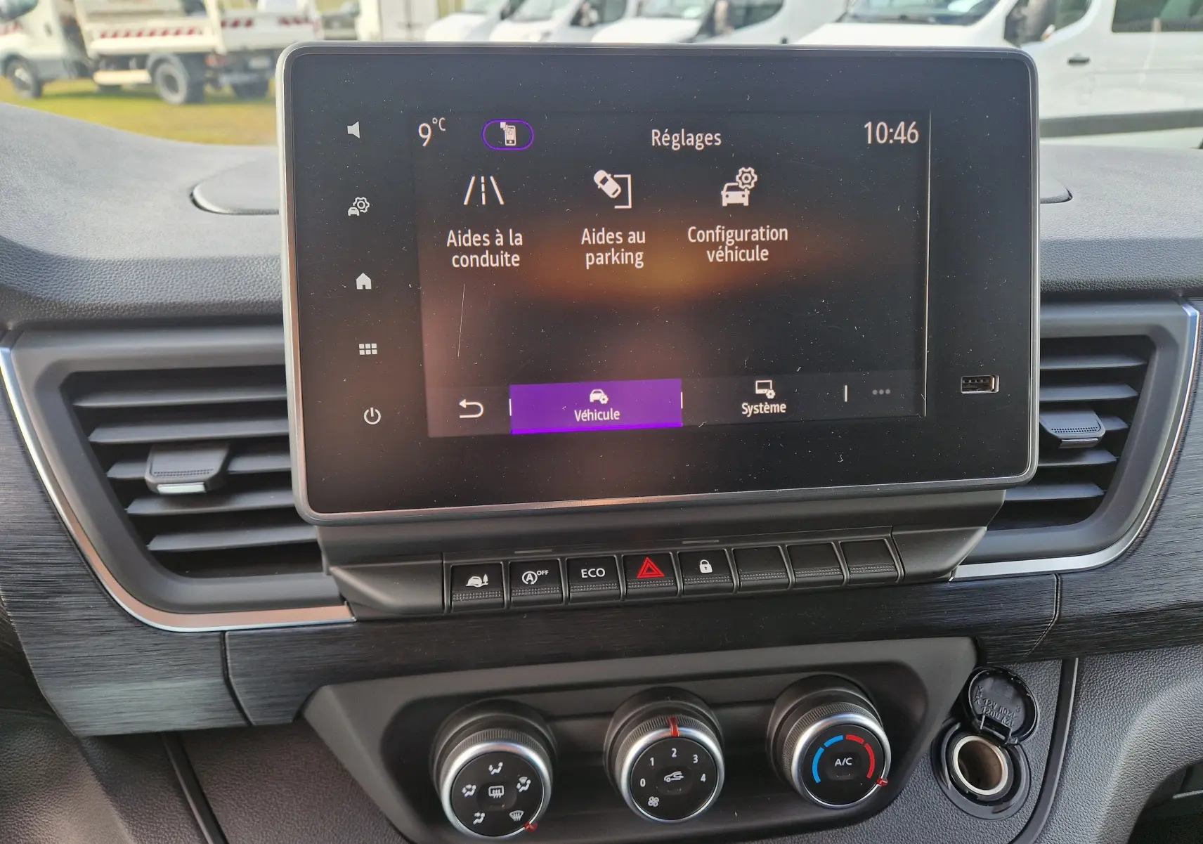 Vue rapprochée de l’écran tactile central et de la console de climatisation du Nissan Primastar blanc 2025.