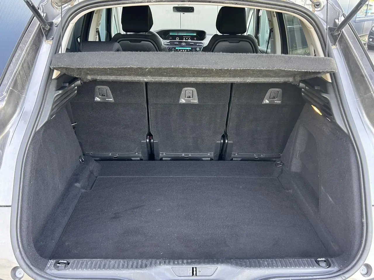 Coffre ouvert vu de l'arrière d'une Citroën C4 Spacetourer gris Platinium avec banquette arrière en tissu noir.