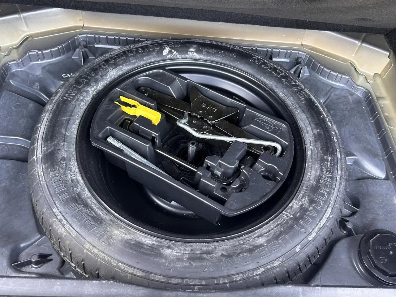 Gros plan sur la roue de secours galette et son kit d'outils dans le coffre d'un Citroën C4 Spacetourer gris Platinium.