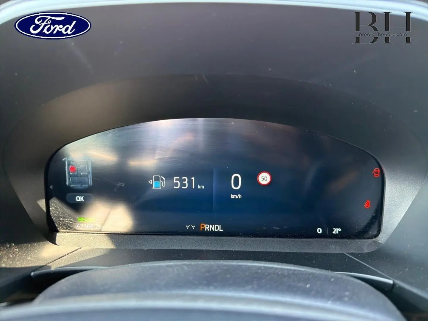 Tableau de bord numérique du Ford Kuga 2025 affichant autonomie, vitesse et indicateurs, vu de face depuis le siège conducteur.