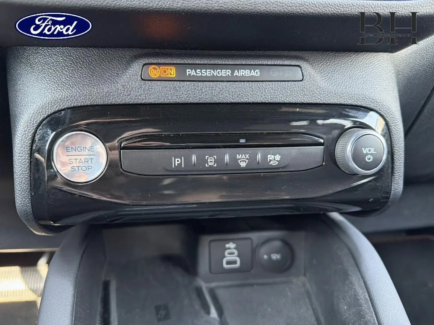 Détail de la console centrale du Ford Kuga 2025, bouton start/stop, commandes de stationnement et volume, finition noire brillante.