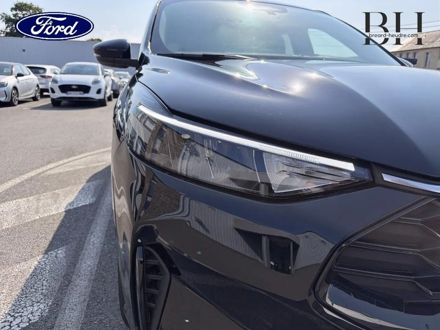 Gros plan sur l'avant droit noir Agate métallisé du Ford Kuga 2025, mettant en valeur le phare LED et la calandre sportive.