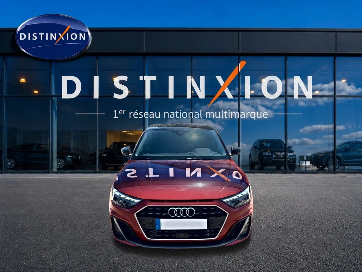 Audi A1 Sportback rouge et noir vue de face, avec calandre hexagonale et phares LED, devant une vitrine Distinxion.