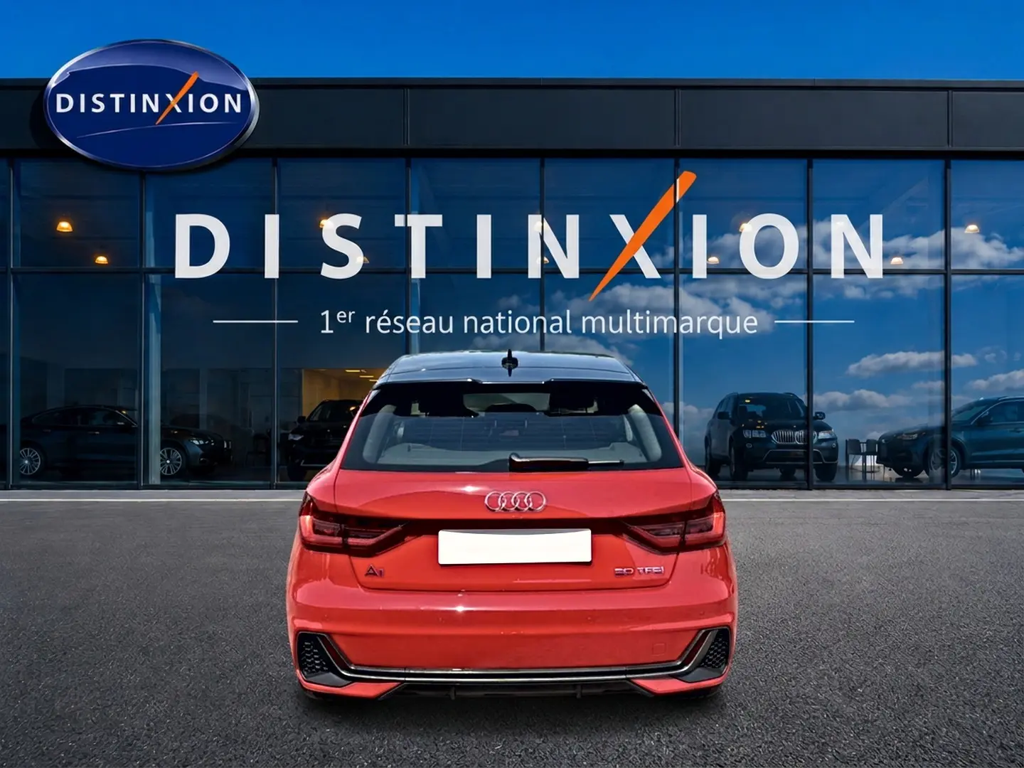 Vue arrière d'une Audi A1 Sportback 30 TFSI rouge et noir, avec becquet et feux arrière LED, devant une vitrine Distinxion.