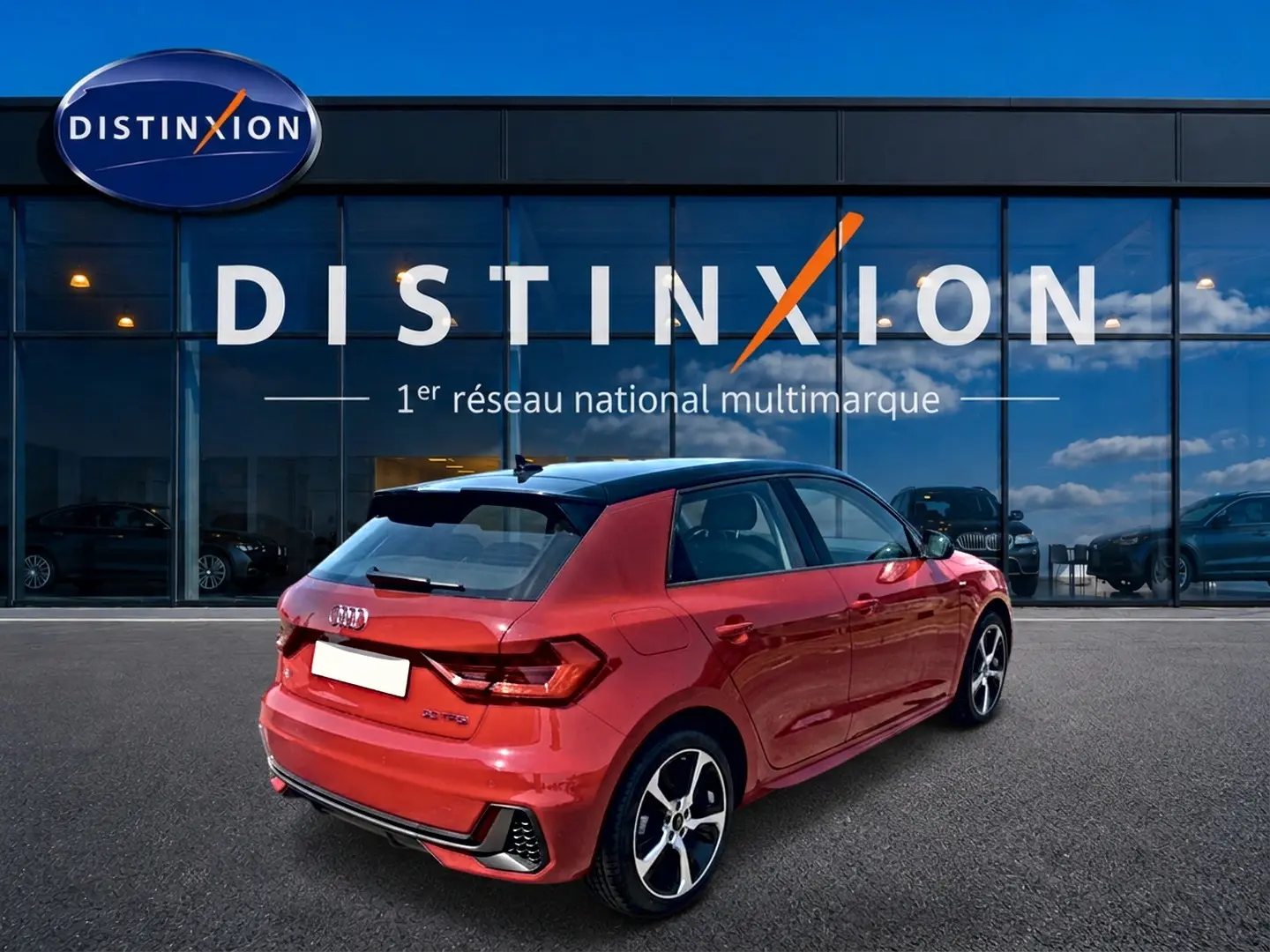 Audi A1 Sportback rouge et noir vue 3/4 arrière droit avec jantes alu et toit noir devant une vitrine Distinxion.