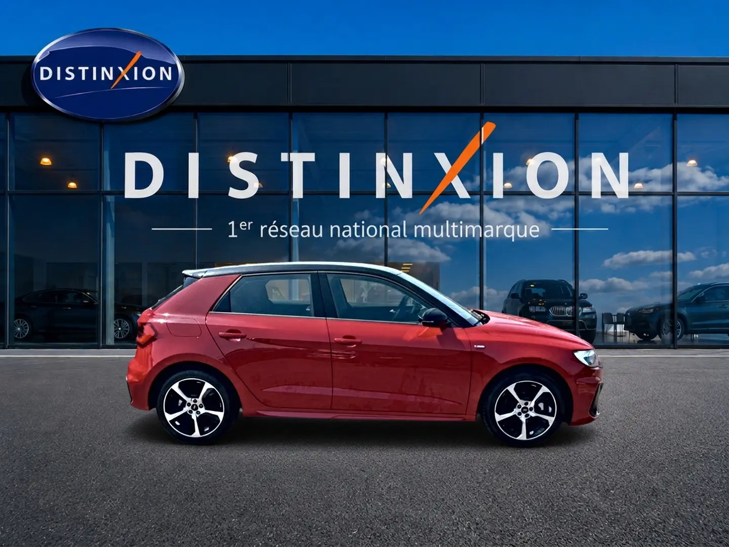 Audi A1 Sportback rouge et noir vue de profil côté gauche devant une vitrine avec logo Distinxion.