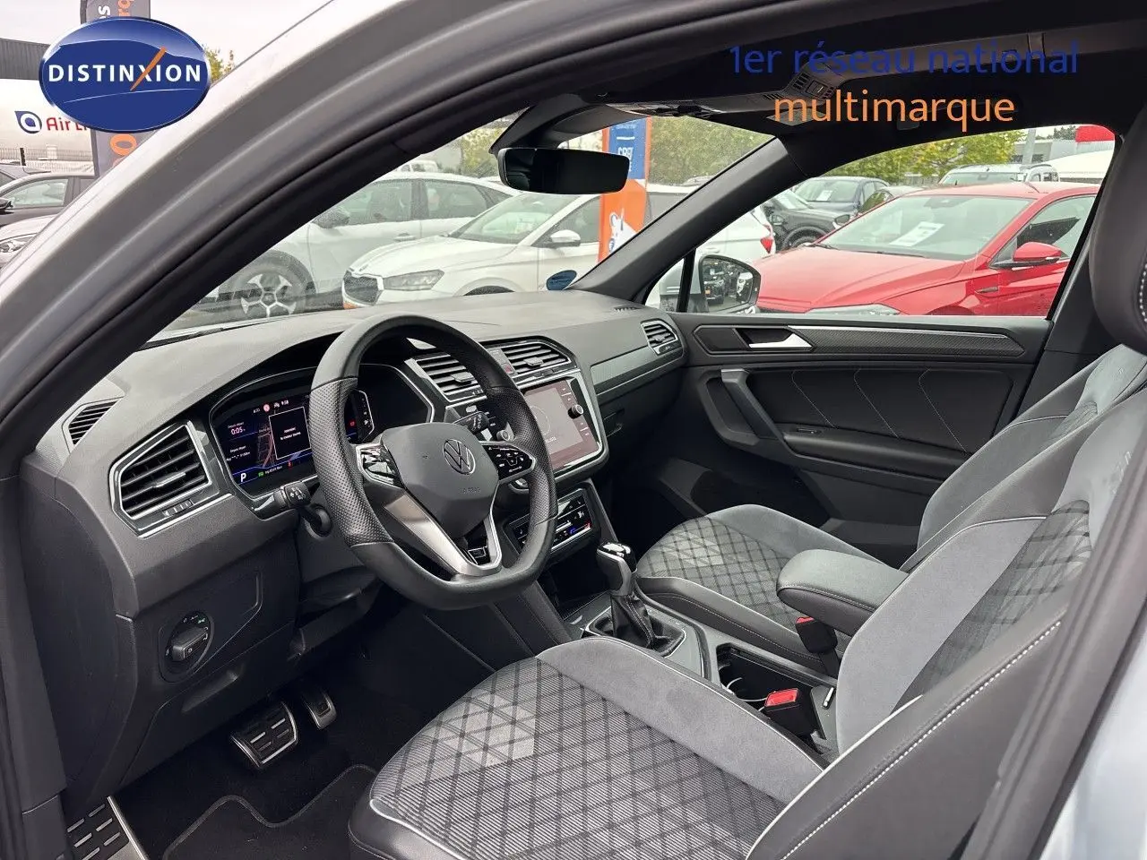 Vue intérieure côté conducteur du Volkswagen Tiguan 2024, montrant le tableau de bord moderne et les sièges gris/noir en tissu et cuir.