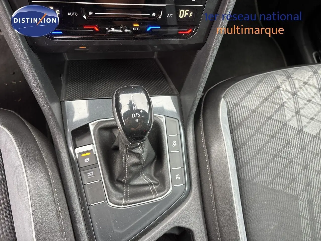 Vue rapprochée de la console centrale du Volkswagen Tiguan 2024 en Reflex Silver, avec levier de boîte auto et sièges tissu cuir.