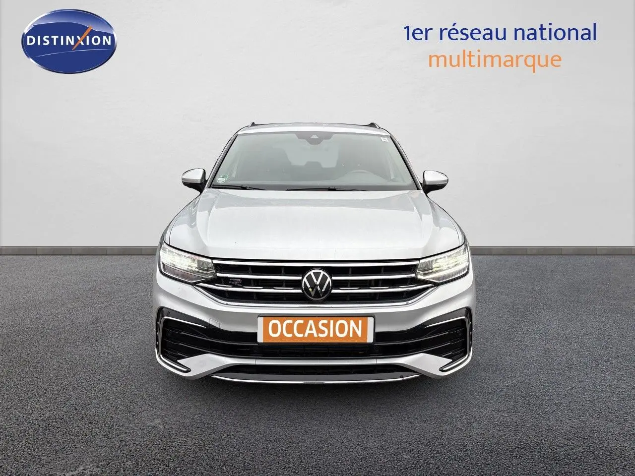 Vue frontale d'un Volkswagen Tiguan 1.5 TSI R-Line 2024 en Reflex Silver Metal avec calandre et phares LED allumés.