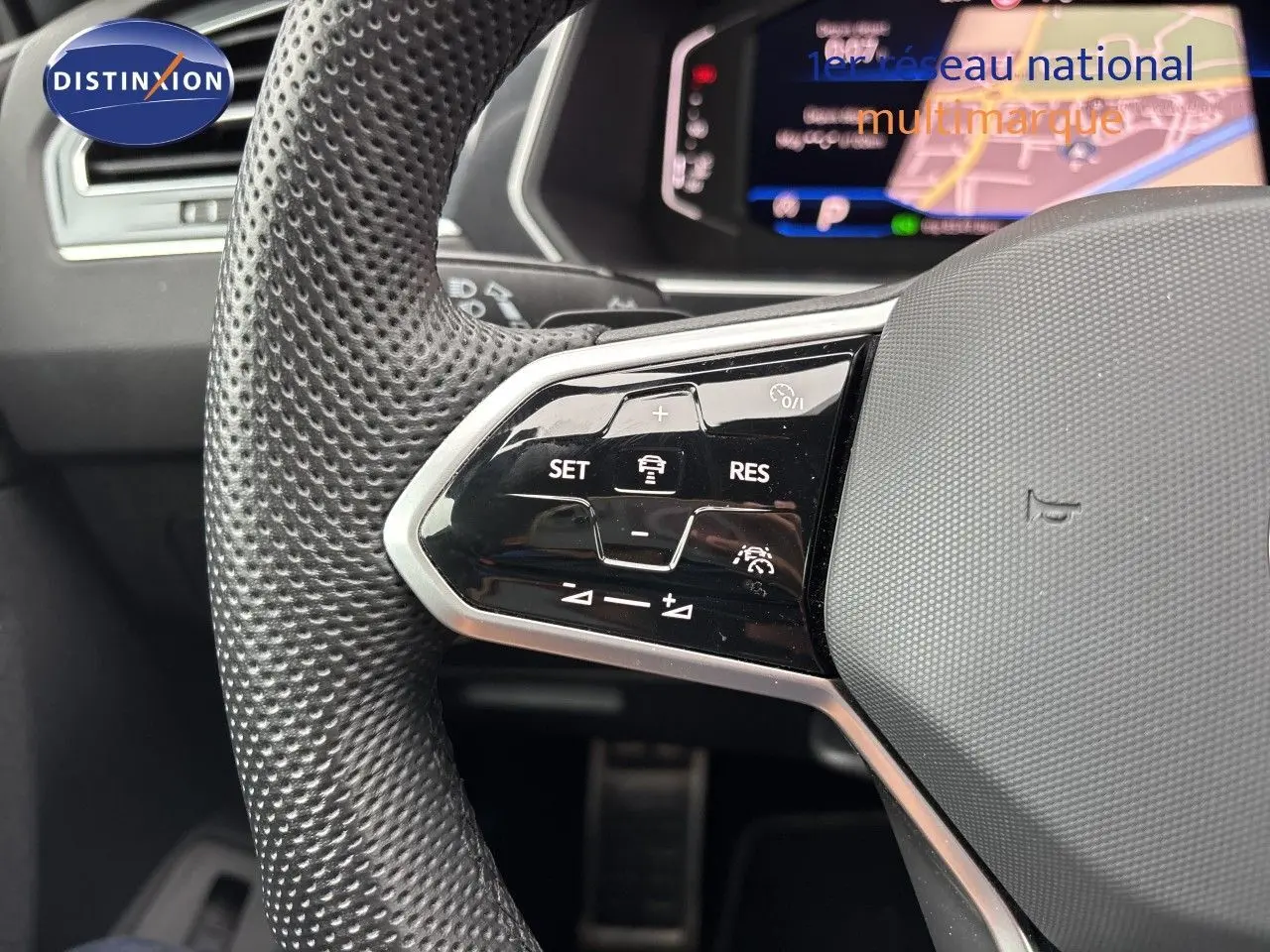 Gros plan sur le volant multifonction en cuir perforé d’un Volkswagen Tiguan 2024 Reflex Silver, avec commandes de régulateur.