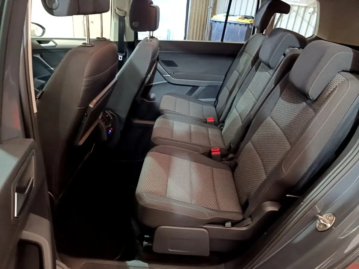 Vue intérieure côté droit des sièges arrière gris foncé du Volkswagen Touran 2023, avec appuie-têtes et ceintures visibles.