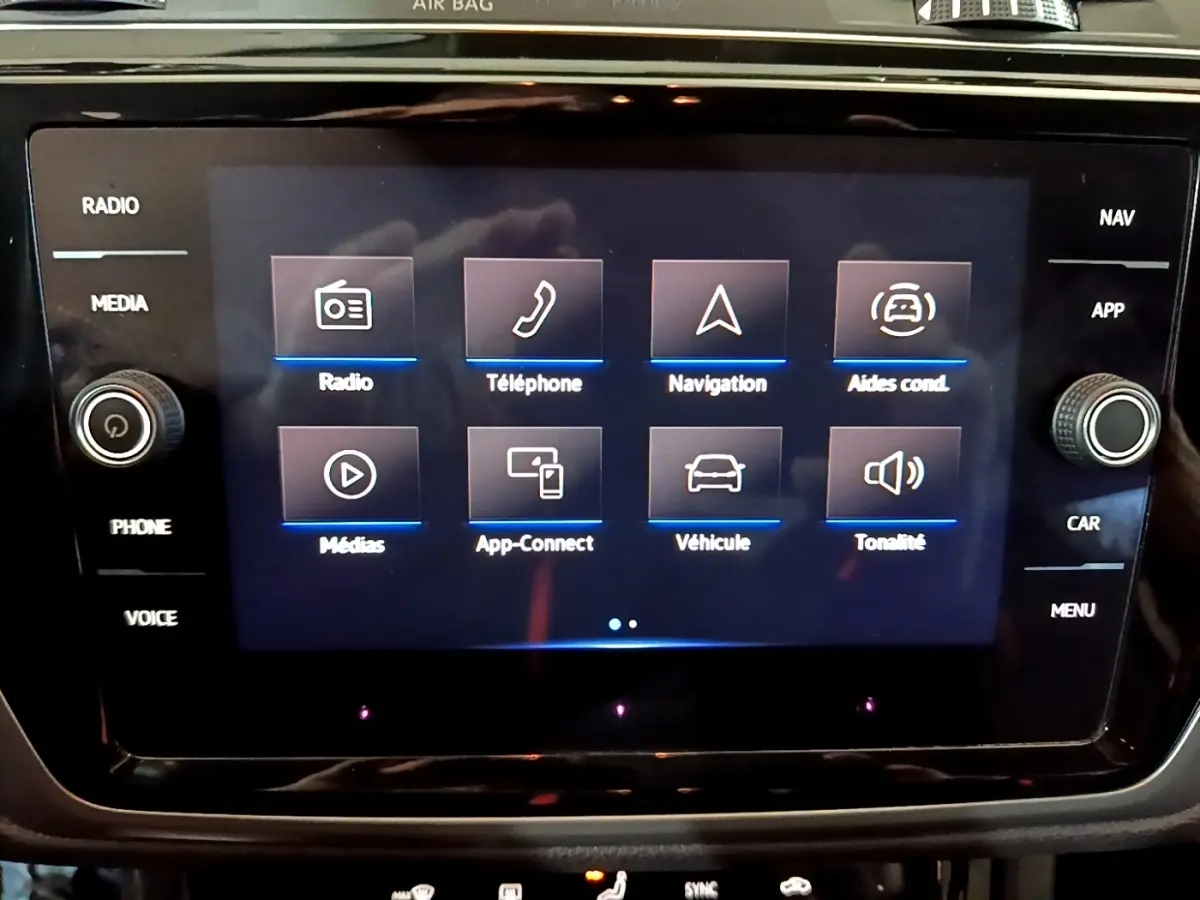 Écran tactile central du Volkswagen Touran 2023 affichant les menus radio, téléphone, navigation et aides à la conduite.