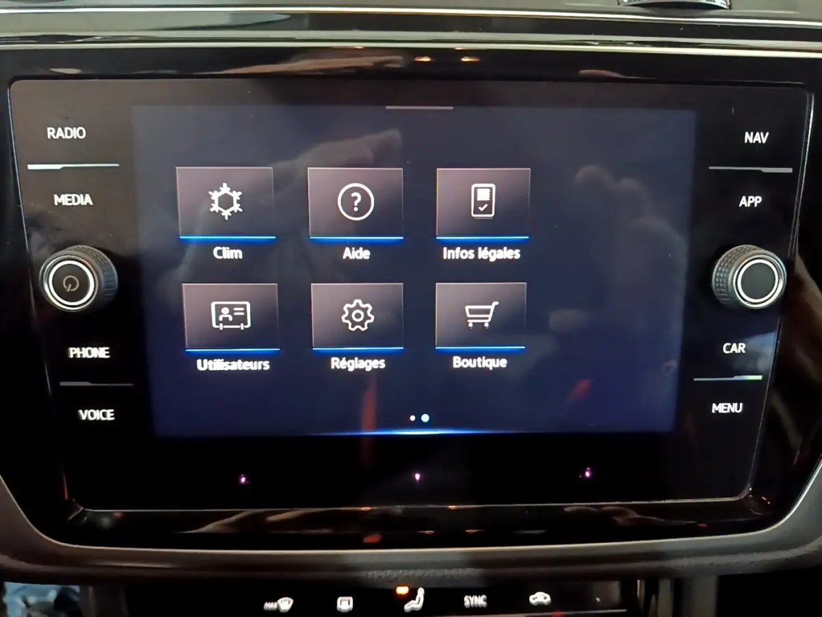 Écran tactile central du Volkswagen Touran gris foncé 2023 affichant les options climatisation, aide et réglages.