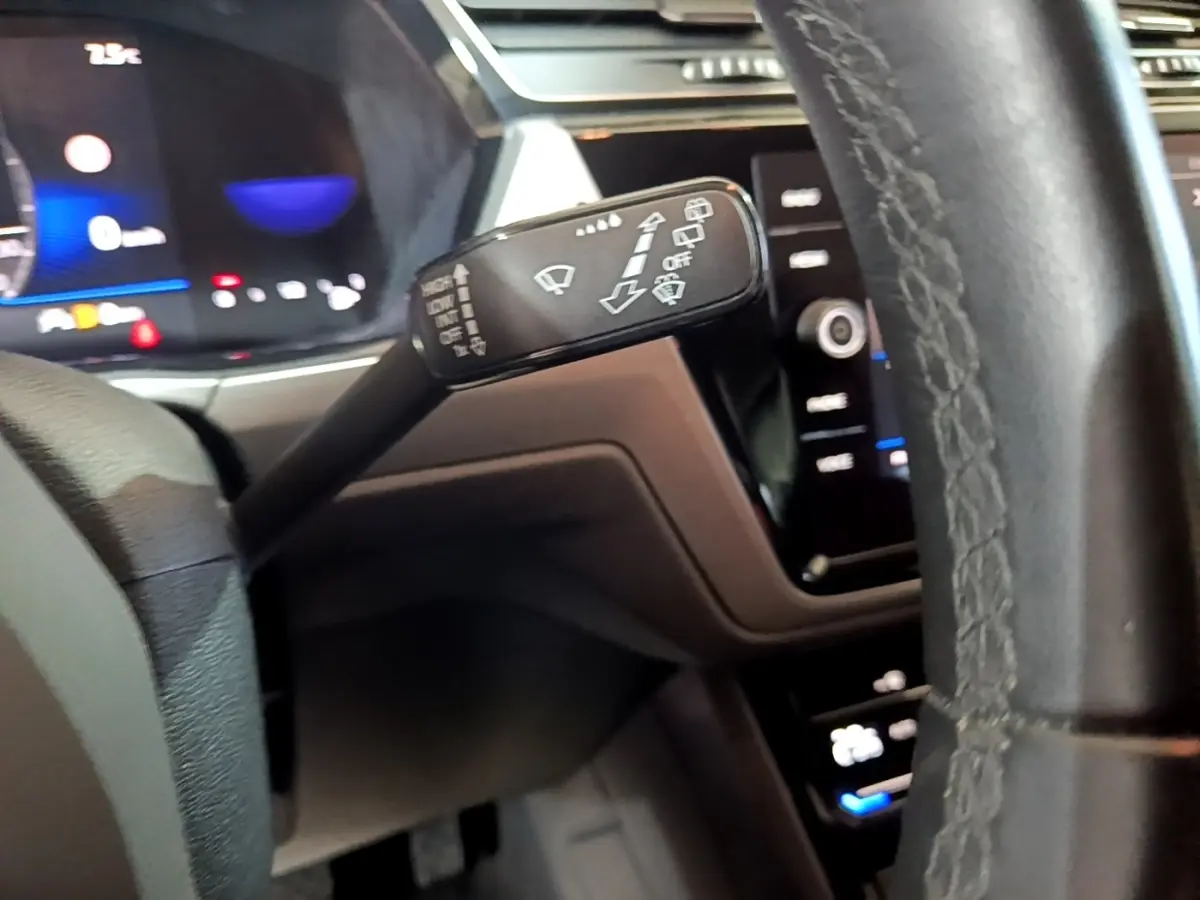 Gros plan sur la manette d’essuie-glace à gauche du volant cuir dans l’habitacle du Volkswagen Touran gris foncé 2023.