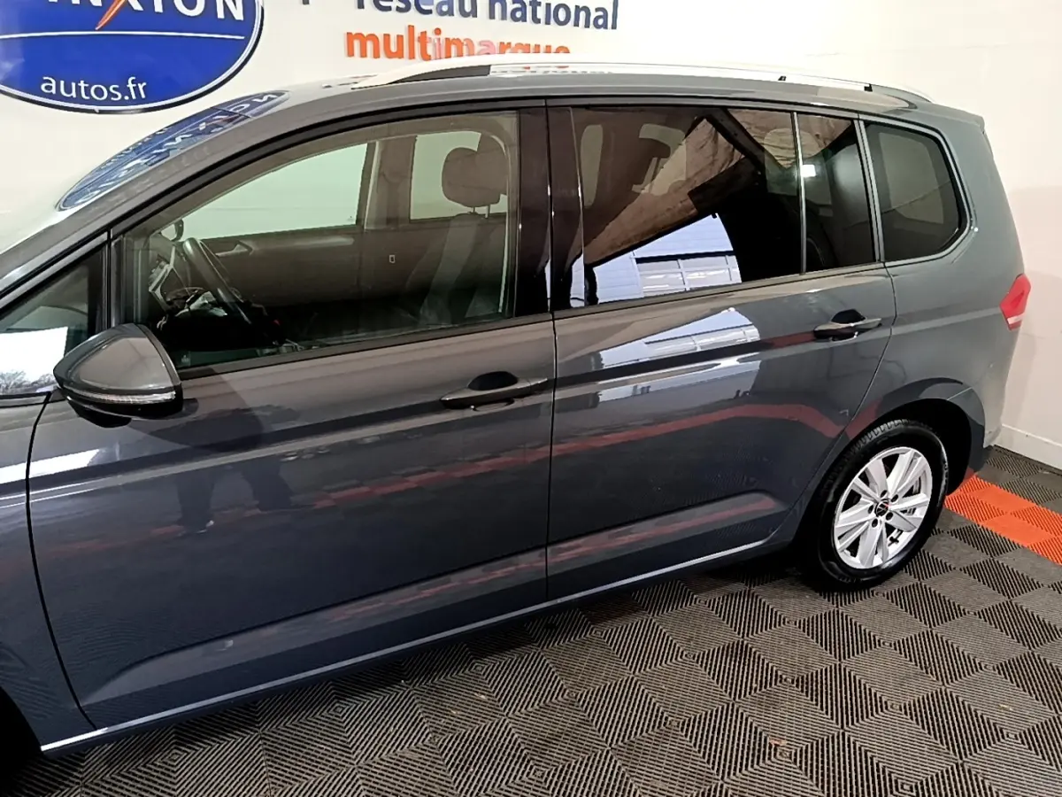 Profil côté gauche d'un Volkswagen Touran gris foncé 2023, avec jantes alliage et vitres teintées.