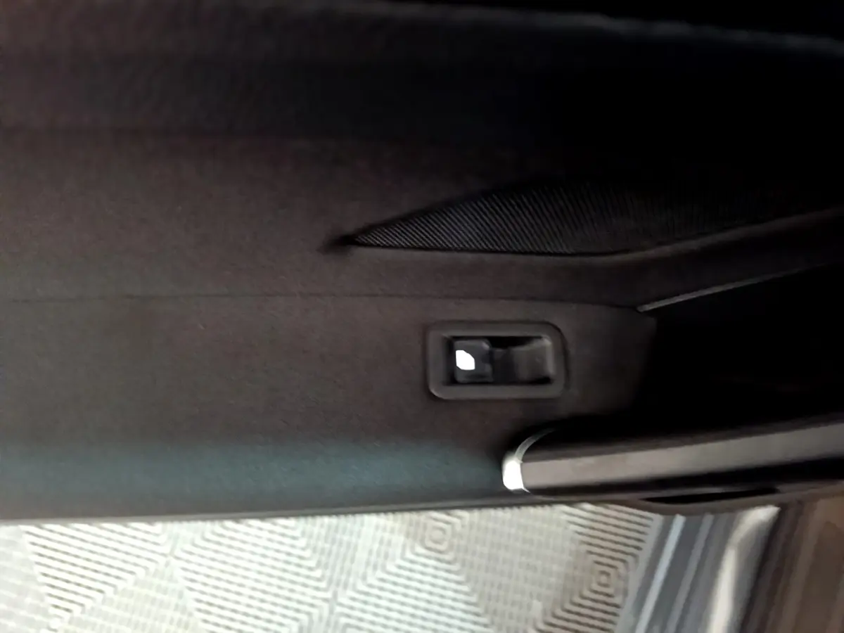 Poignée intérieure de porte arrière droite du Volkswagen Touran gris foncé 2023 avec habillage tissu noir.