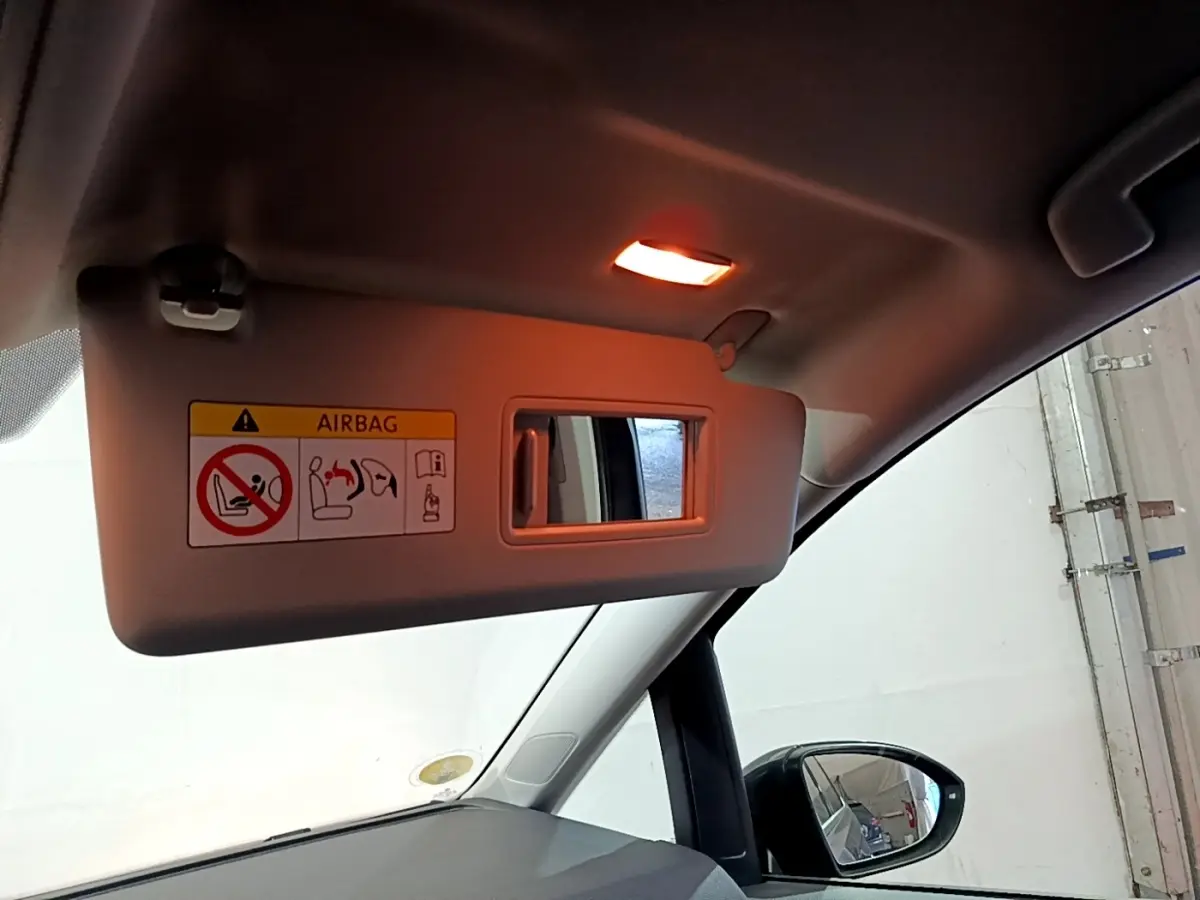 Détail du pare-soleil côté conducteur avec miroir et avertissement airbag dans un Volkswagen Touran gris foncé 2023.