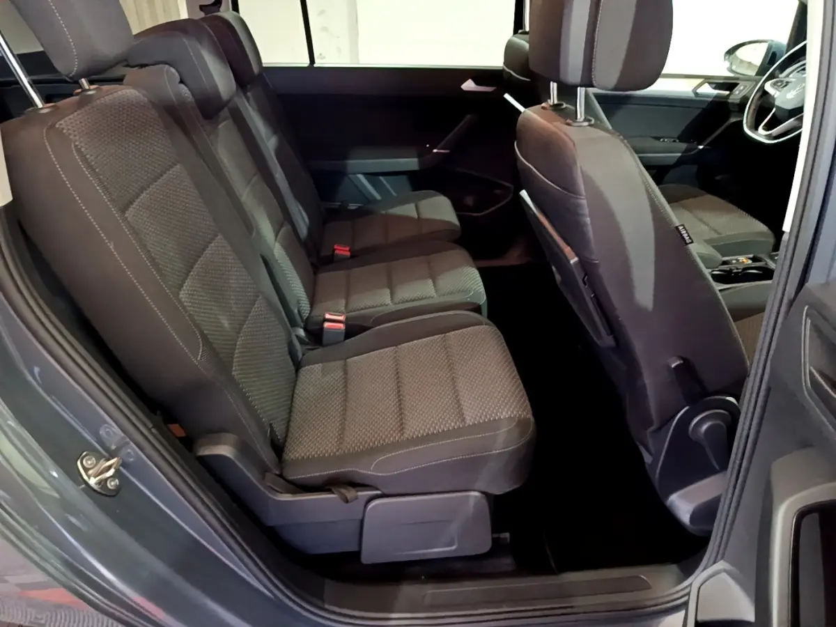 Vue intérieure côté gauche sur les sièges arrière noirs du Volkswagen Touran gris foncé 2023, avec détails tissu et appuie-têtes.