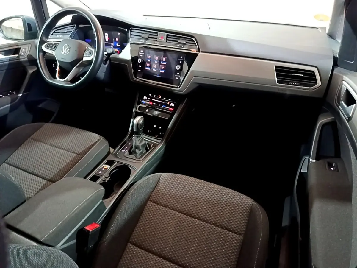 Intérieur avant du Volkswagen Touran 2023 gris foncé, vue côté conducteur avec tableau de bord digital et écran tactile central.