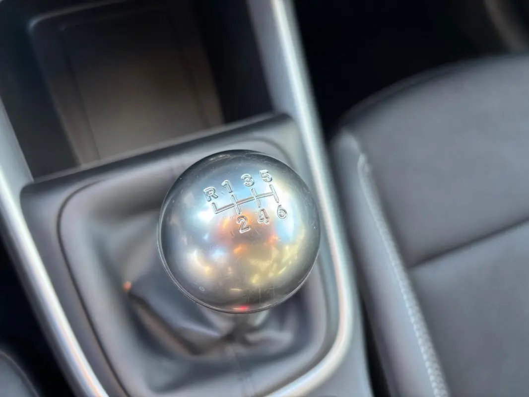 Gros plan sur le levier de vitesses manuel argenté du Jeep Avenger noir, avec siège conducteur en tissu gris visible à droite.