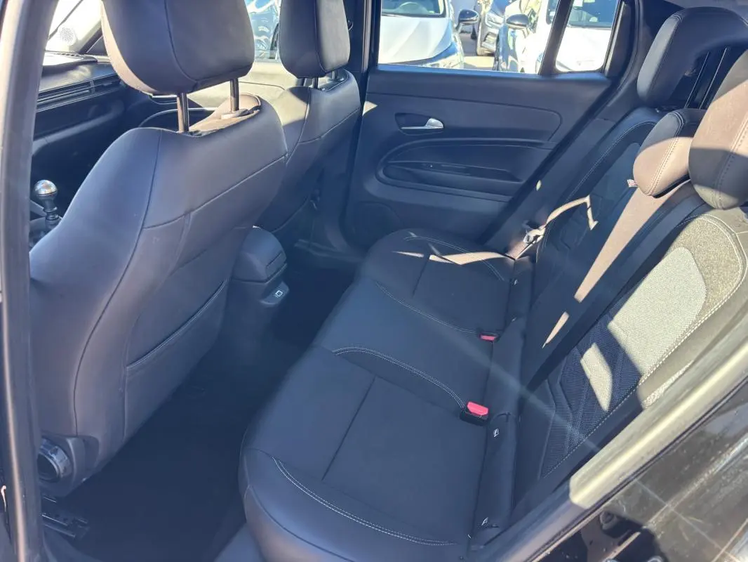 Vue intérieure arrière côté droit du Jeep Avenger noir 2024, montrant les sièges en tissu et cuir avec appuie-têtes.