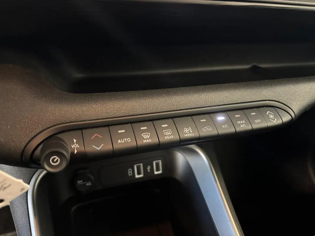 Vue intérieure du tableau de bord du Jeep Avenger noir 2024, montrant les commandes de climatisation et les ports USB.