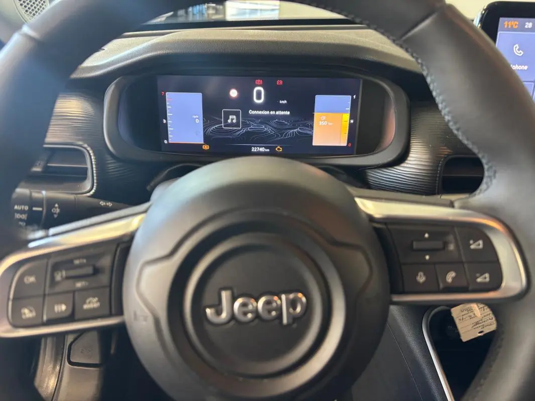 Vue rapprochée du tableau de bord et volant noir du Jeep Avenger 2024 avec affichage numérique et commandes intégrées.