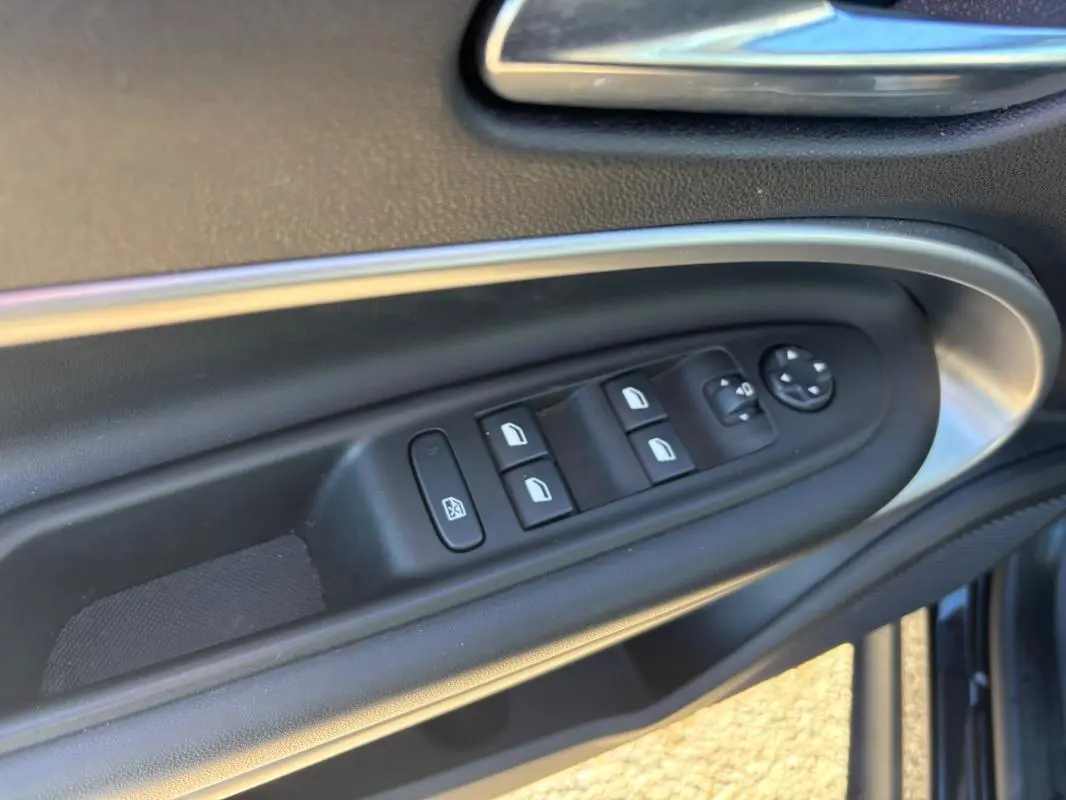 Détail des commandes des vitres électriques et rétroviseurs sur la porte côté conducteur d’un Jeep Avenger noir 2024.