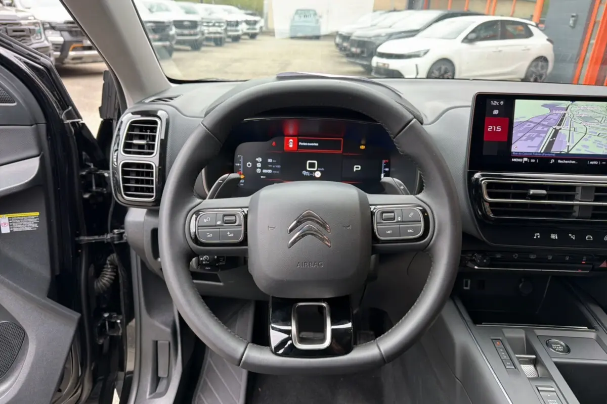 Vue intérieure centrée sur le volant cuir noir et le tableau de bord digital d'une Citroën C5 Aircross 2025.