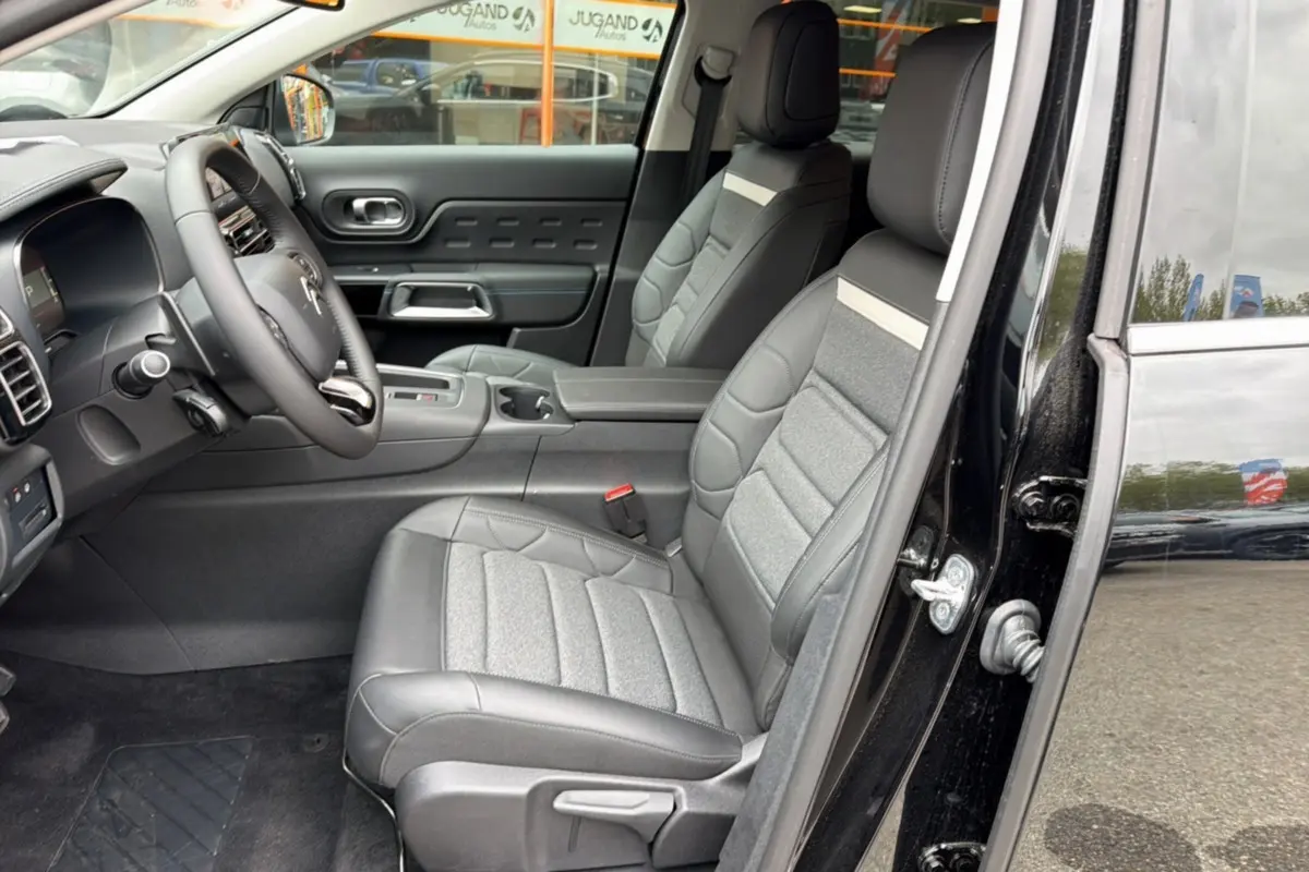Vue intérieure côté conducteur du Citroën C5 Aircross noir 2025, sièges cuir et tissu, volant multifonctions visible.