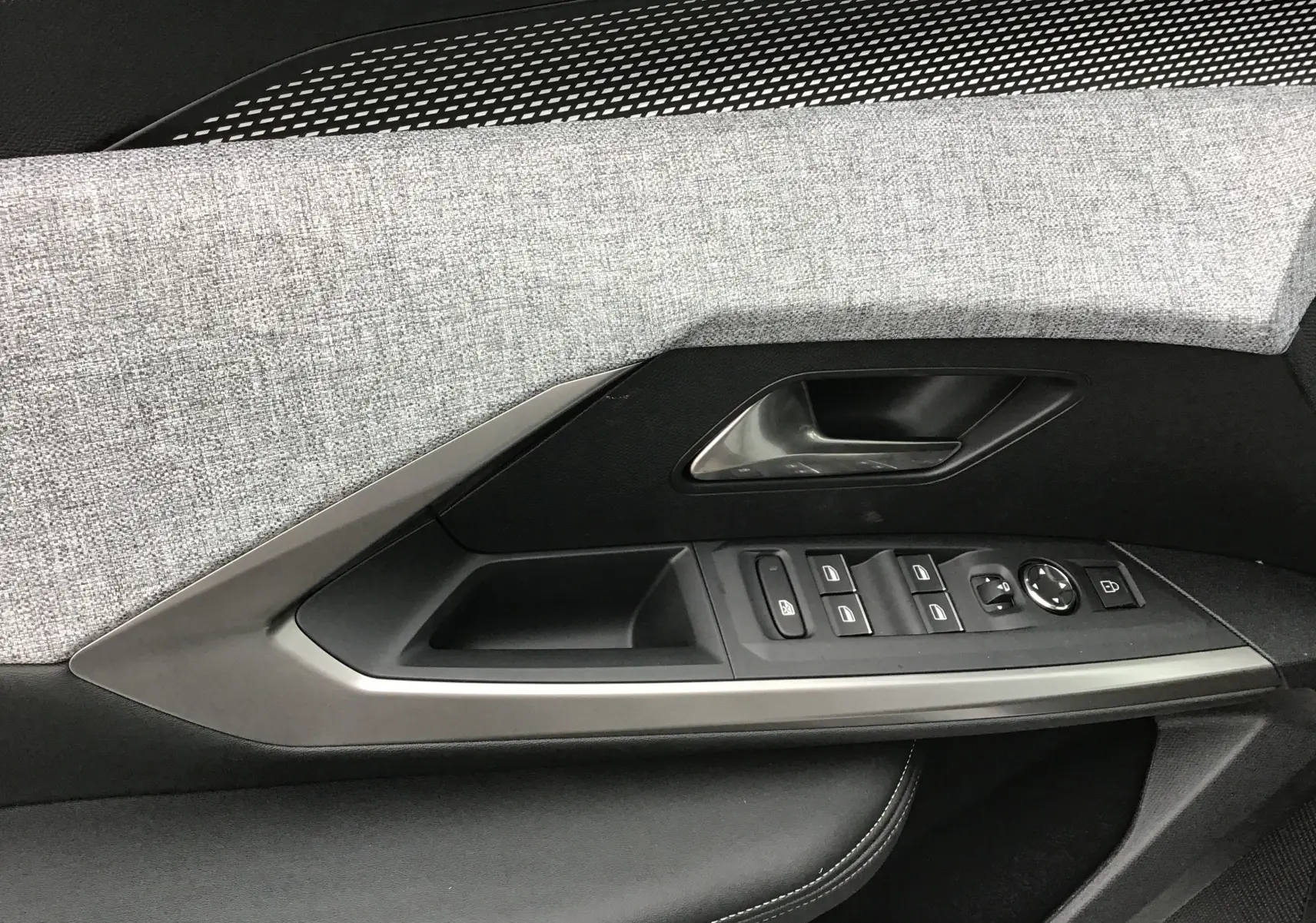 Détail de la porte côté conducteur du Peugeot 3008 2026, avec tissu gris clair et commandes électriques intégrées.