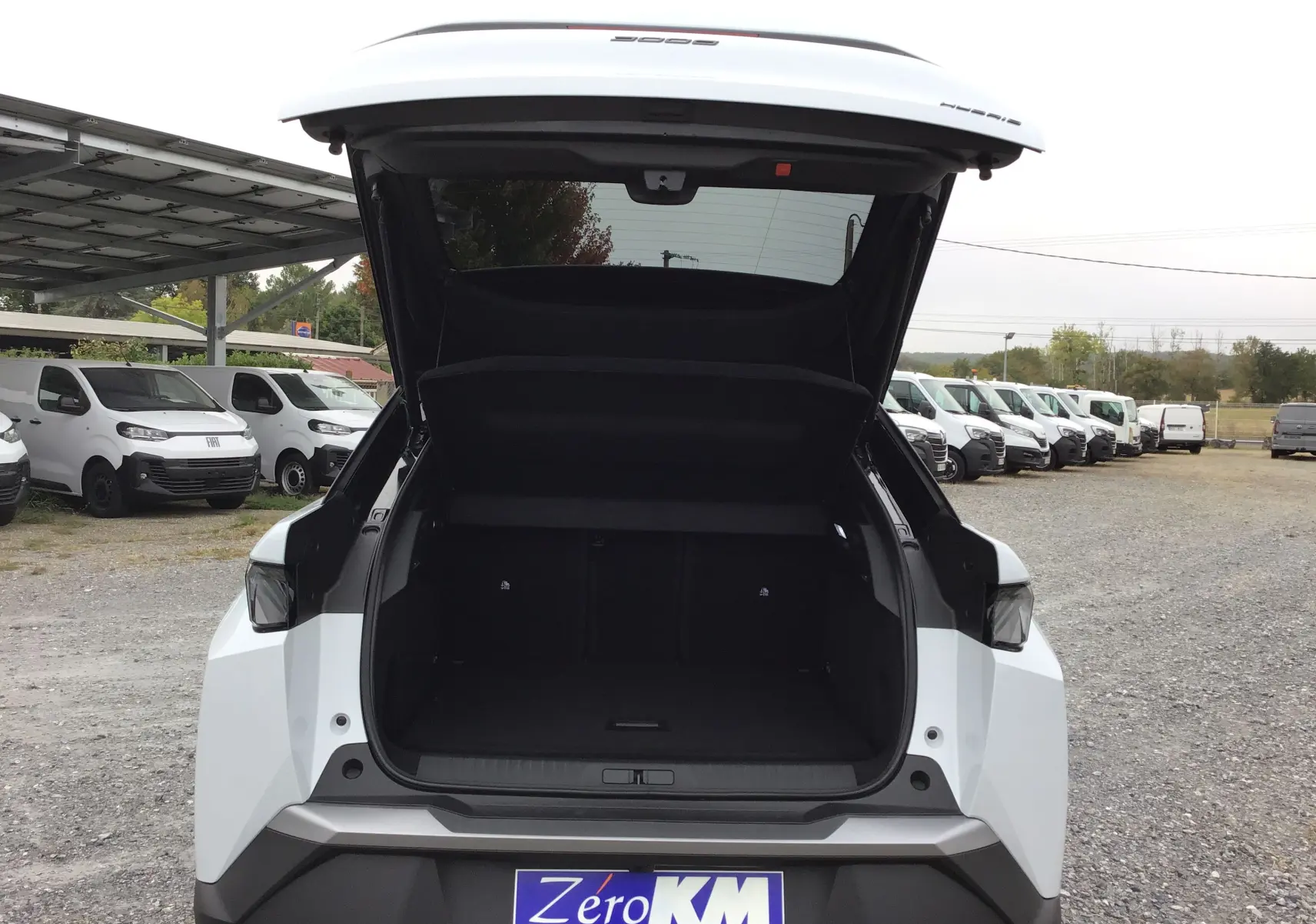 Vue arrière du Peugeot 3008 blanc Okenite avec coffre ouvert, mettant en valeur l'espace de chargement et le logo Zéro KM.