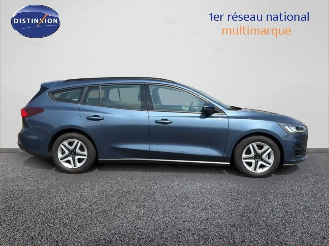 Ford Focus SW bleu foncé vue de profil côté gauche, avec barres de toit et jantes classiques 16 pouces.