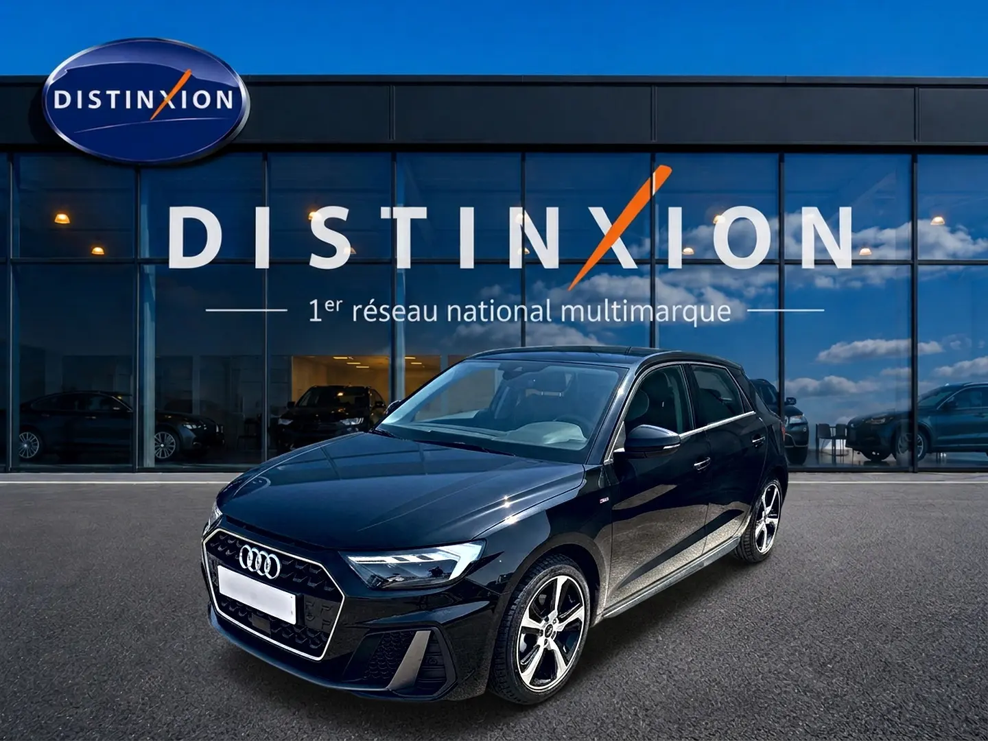 Audi A1 Sportback noir vue 3/4 avant droit, avec jantes alu et calandre hexagonale S line devant un showroom Distinxion.